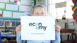 Schoolgirl holds up paper economy logo