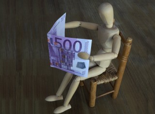 A manikin sits on a chair and reads a 500 Euro note instead of a newspaper. Credit: S. Steinach