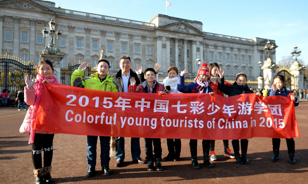 A group of Chinese tourists pose for photographs outside Buckingham Palace, London