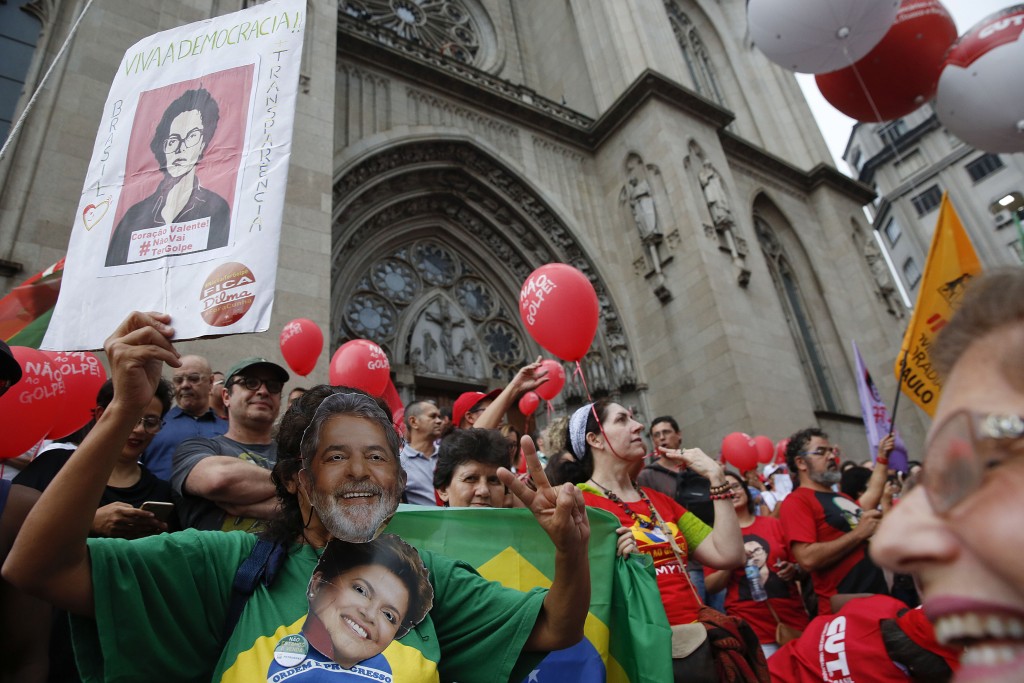 A demonstrator wearing a mask with the likeness of former Brazilian President Luiz Inacio Lula da Silva and holding a picture of Brazil's current president Dilma Rousseff protests in their support in Sao Paulo, Brazil