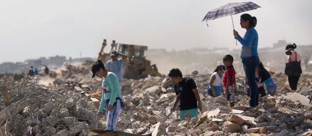 Residents comb through a field, salvaging recyclable material from post-earthquake debris, in Manta, Ecuador,.