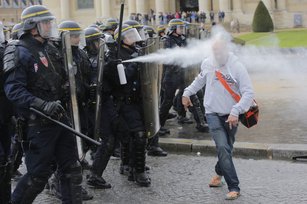 French riot police spray pepper gas at a demonstrator during a protest against changes to Labor Laws in Paris