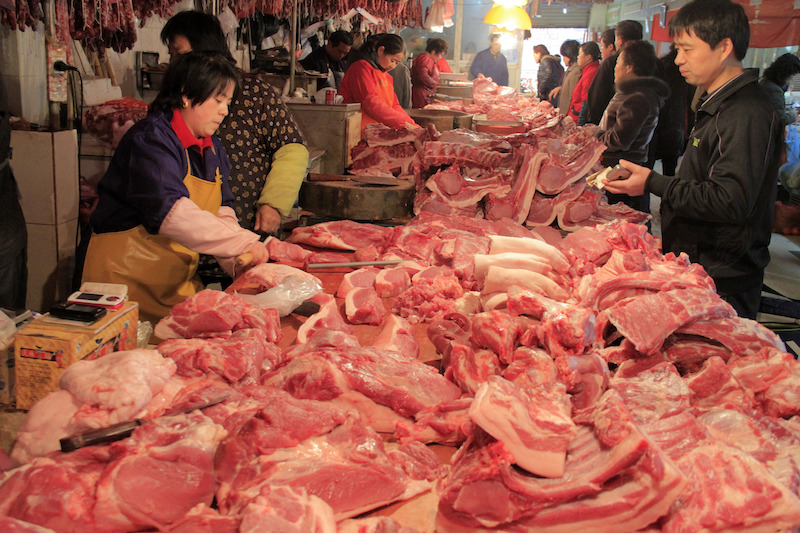 Local residents choose pork at a market in Nanjiang in east China's Jiangsu province