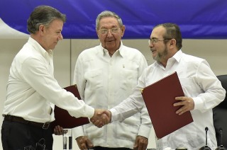 Colombian President Juan Manuel Santos (L) shakes hands with Timoleon Jimenez (R), the top leader of the Revolutionary Armed Forces of Colombia (FARC), next to Cuban President Raul Castro, in the signing ceremony of a historic ceasefire agreement between the Colombian government and the FARC, in Havana, capital of Cuba, on June 23, 2016.
