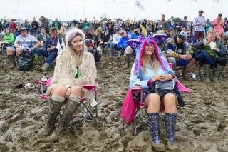 The crowd at the Glastonbury Festival sit on chairs in the mud, at Worthy Farm in Somerset.
