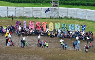 A flash-mob gather in front of the Glastonbury sign at Glastonbury Festival 2016