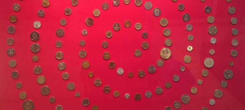 A circle of coins on a red background, part og the Money Matters exhibition at the British Museum