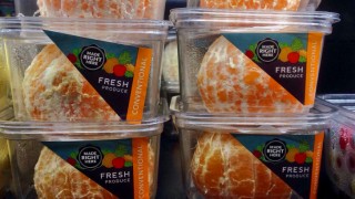 Some pre-peeled oranges on a shop shelf