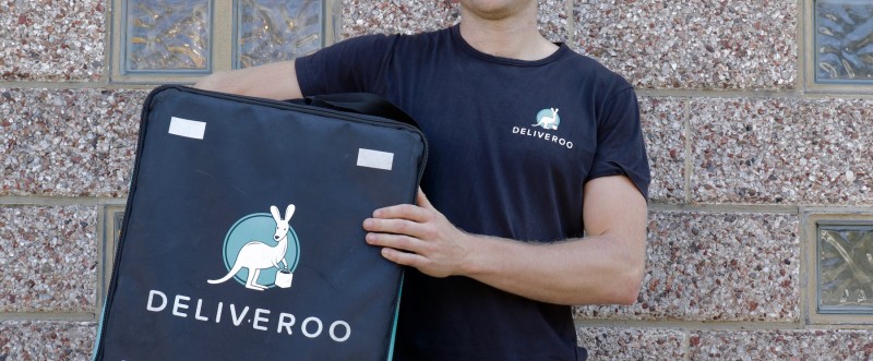 A Deliveroo driver holds his delivery box