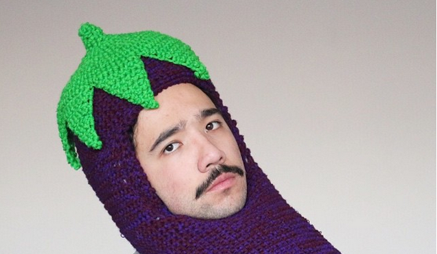 A man wears a knitted eggplant balaclava