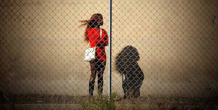A Nigerian sex worker stands behind a fence in Italy