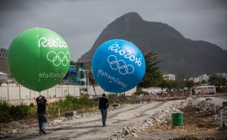 Workers with large balloons, featuring the writing 'Rio 2016', walk past the olympic park in Rio