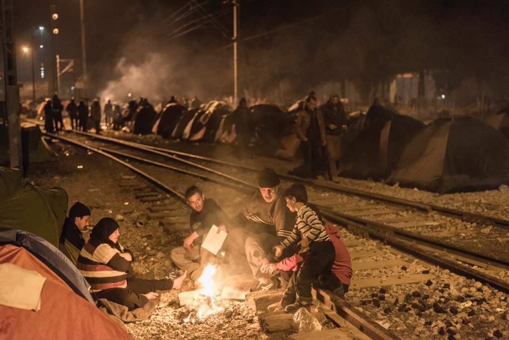 Refugees sit round a campfire in Idomeni