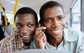 Two smiling men talking on mobile phones