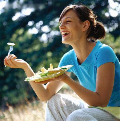 A smiling woman eating salad