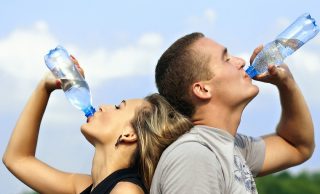 Two people drinking bottles of water