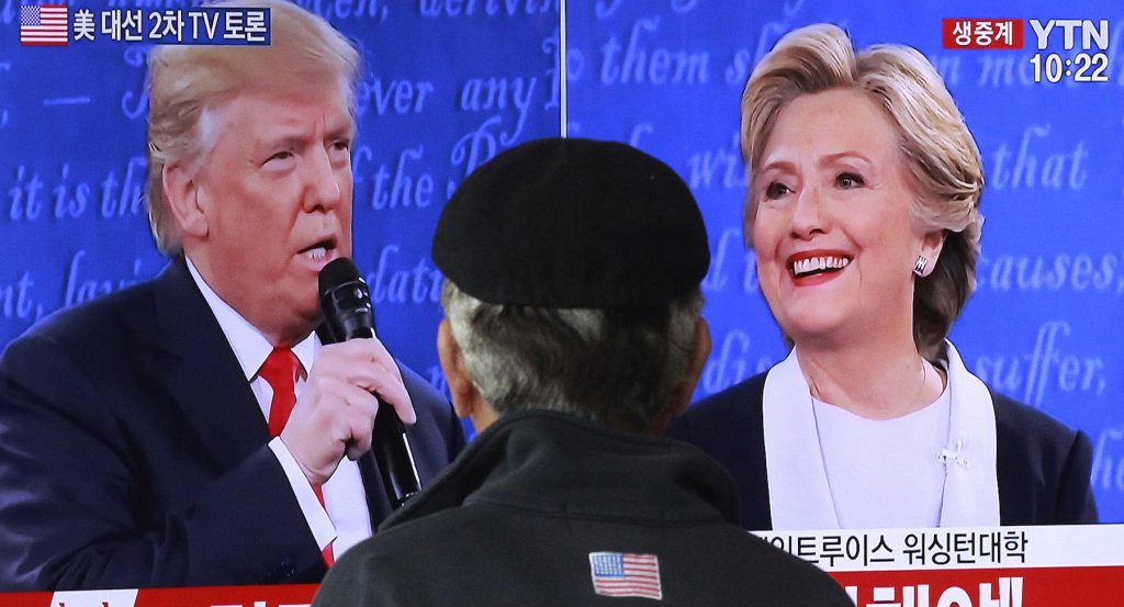 A man watches a TV screen showing the live broadcast of the US presidential debate.