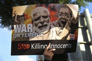 A person holds up a protest poster against the war in Yemen