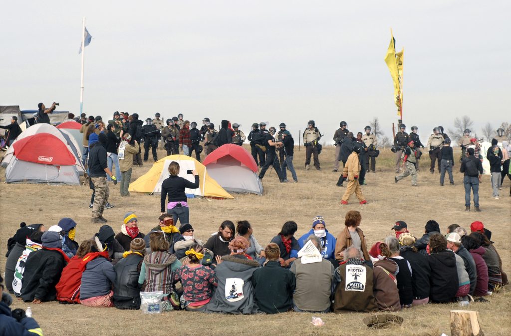 Native Americans sit opposite law enforcement officers in North Dakota, USA.