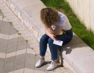 a-distressed-girl-sits-on-the-parapet-holding-a-letter-in-her-hands-holding-a-paper-and-experiencing_t20_Enx2oQ (1)