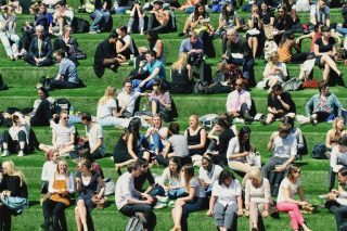 students-and-friends-chatting-and-laughing-as-they-gather-for-their-lunch-break-on-a-grassy-hill-in_t20_oEV6jk