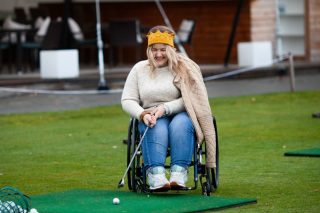 a-girl-in-a-wheelchair-plays-golf-woman-laughs-and-holds-a-golf-club_t20_lL9WZb