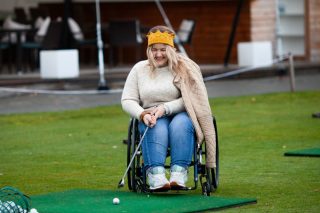 a-girl-in-a-wheelchair-plays-golf-woman-laughs-and-holds-a-golf-club_t20_lL9WZb