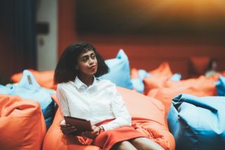 portrait-of-a-young-beautiful-african-american-businesswoman-sitting-on-an-orange-cushion-with-a_t20_xXK028