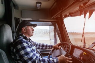 driver-in-cabin-of-big-modern-truck-vehicle-on-highway_t20_zndLjJ