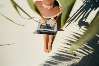 woman-freelancer-travel-and-working-on-the-beach-working-remotely-on-the-laptop-computer-through-the_t20_kR67Z3