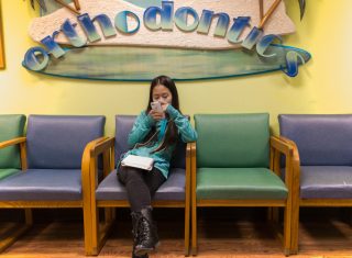 asain-teenage-girl-at-the-dental-office-waiting-room-using-smartphone_t20_VKl7b7