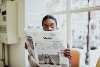 fashionable-millennial-woman-reading-the-newspaper-in-a-laundry-mat_t20_oRR1B4