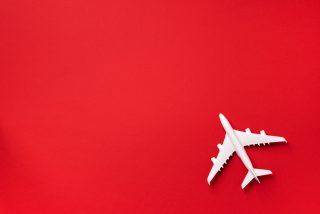 White plane, airplane on red color background with copy space. Top view, flat lay. Minimal style design. Travel, vacation concept