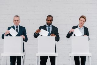 multicultural voters putting ballots in voting boxes